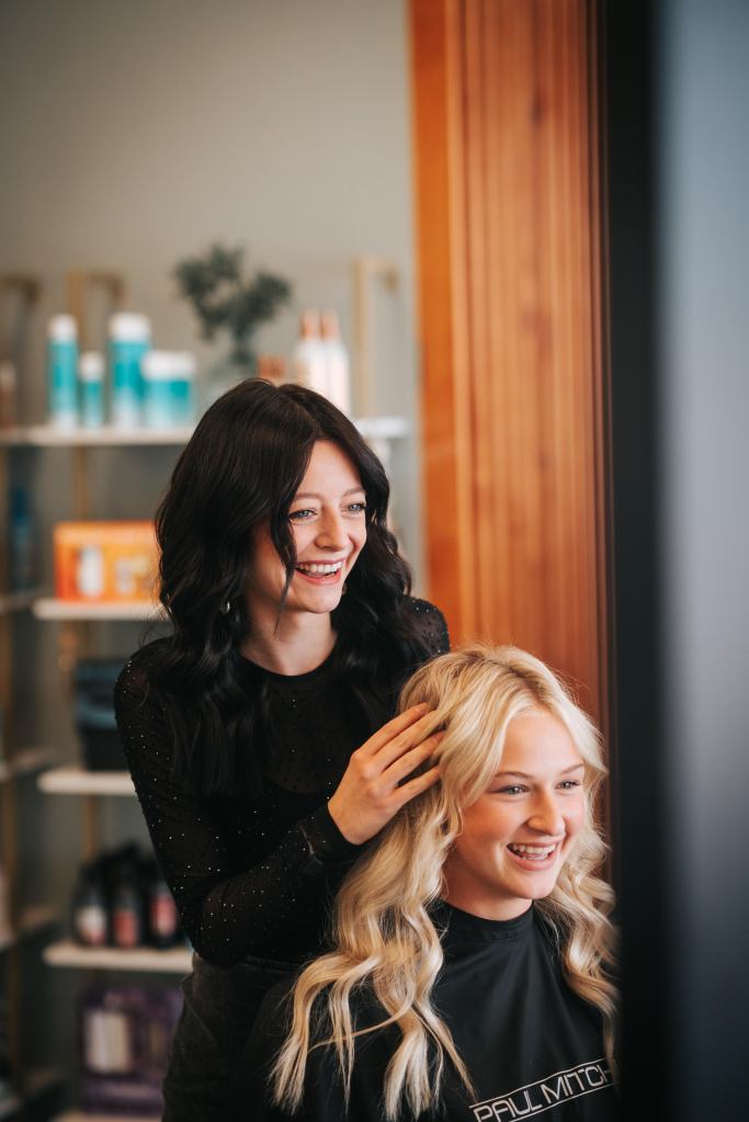 Hairstylist Sarah fluffs the curls of her client.